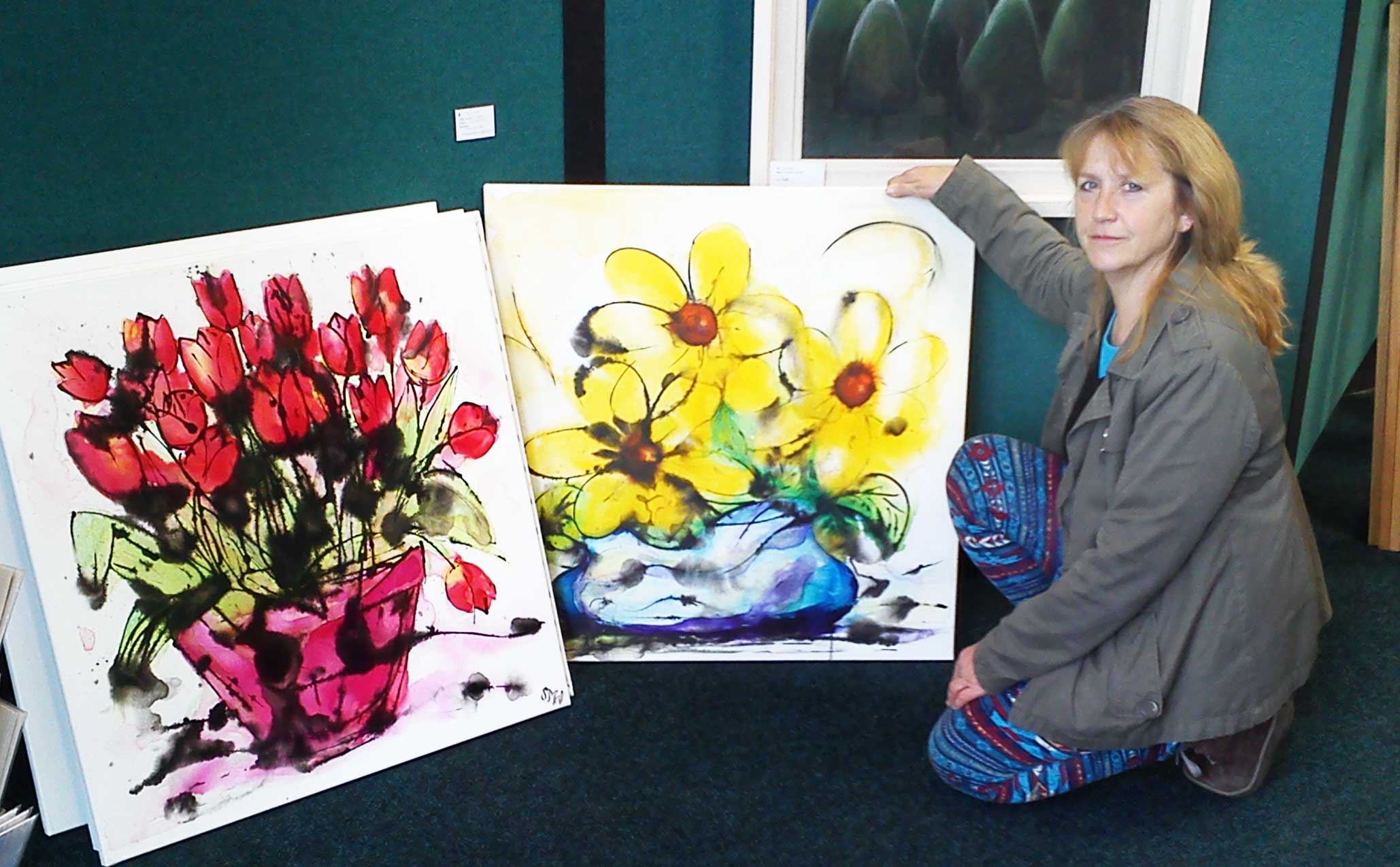 Artist Susan Marie Williams with two large floral paintings from her Fantastic Flowers collection